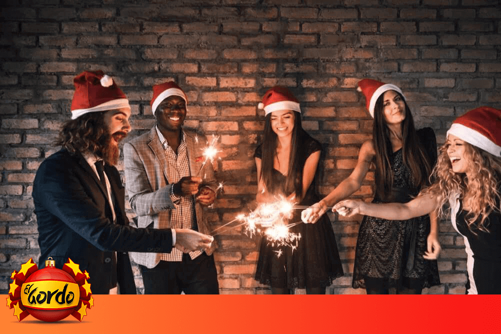 Grupo de amigos usan gorros de navidad y encienden luces de bengala para celebrar sus premios en la Lotería de Navidad española
